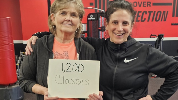 Two members holding a sign that says 1,200 classes